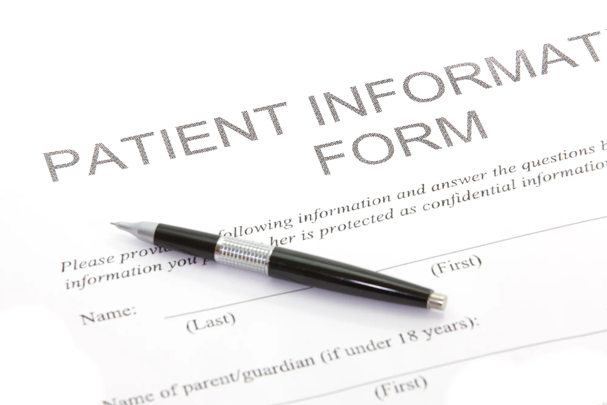 A printed patient information form with a pen resting on it