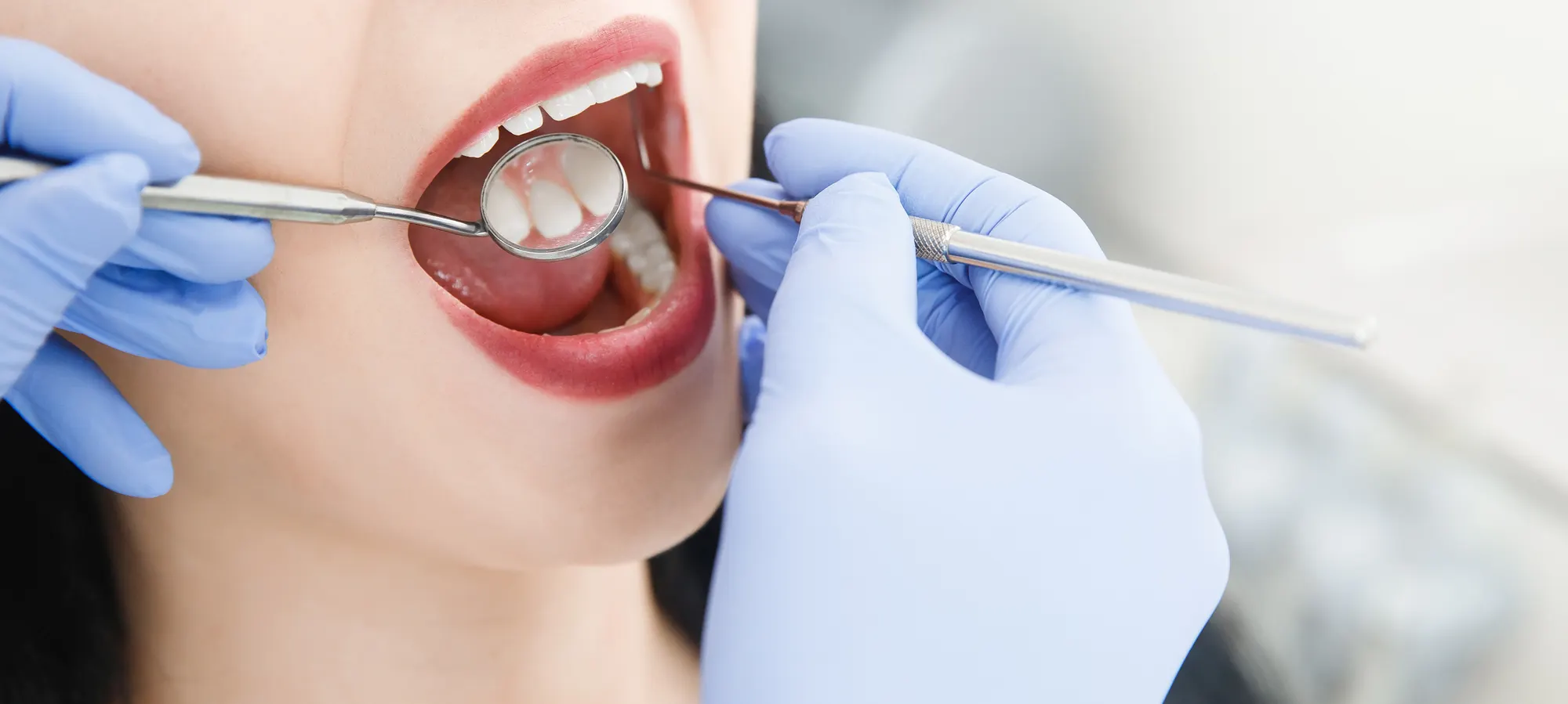 A smiling woman having her teeth examined by a dentist