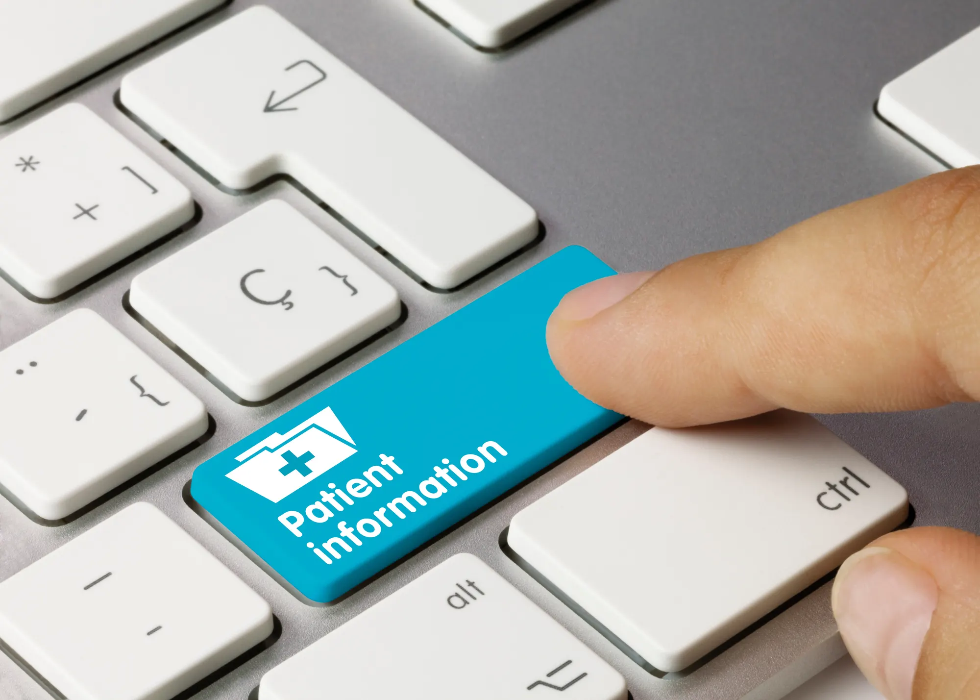A finger pressing a blue keyboard key labeled Patient information